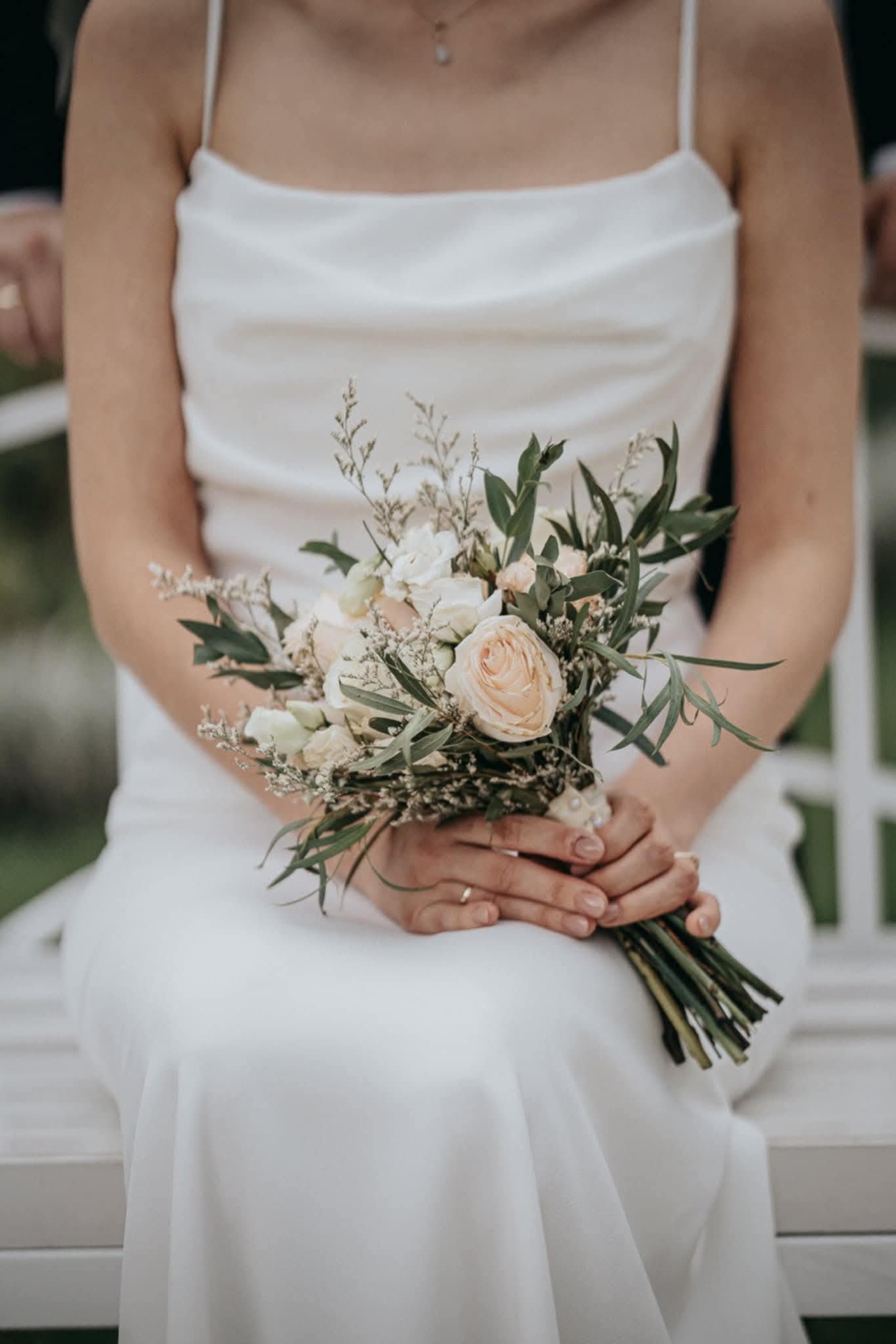 Panna młoda w minimalistycznej i eleganckiej sukni ślubnej na ramiączkach trzymająca naturalny bukiet z róż Viola Figura realizacja Warszawa Śródmieście